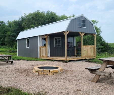 Pre-built Deluxe Cabin sitting in rural setting with fire pit, finished in gray.