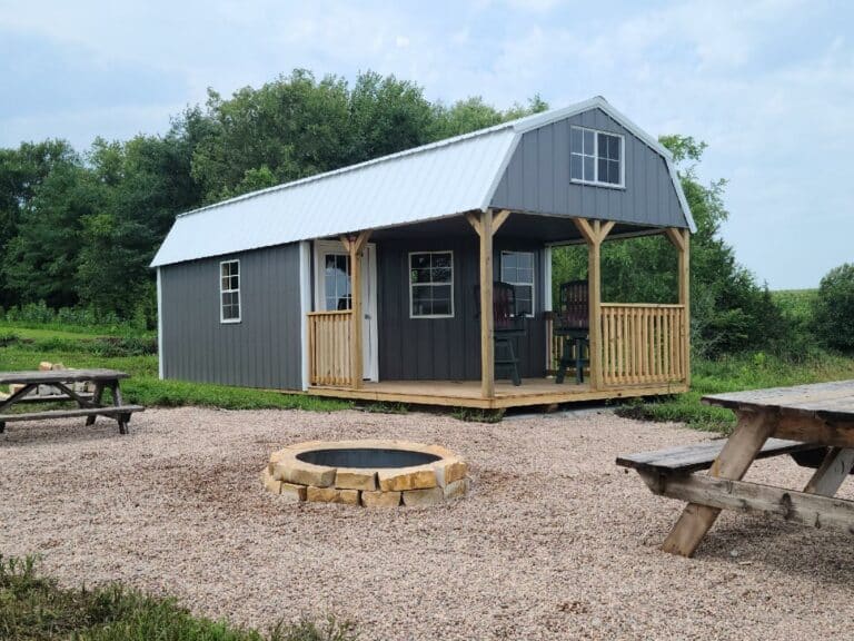 Pre-built Deluxe Cabin sitting in rural setting with fire pit, finished in gray.