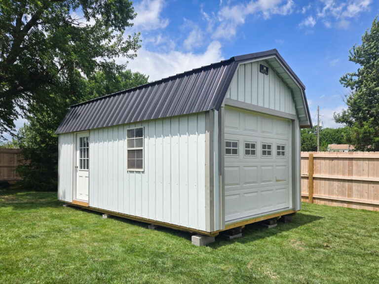Lofted Garage white metal siding with tan trim dark metal roof and overhead door