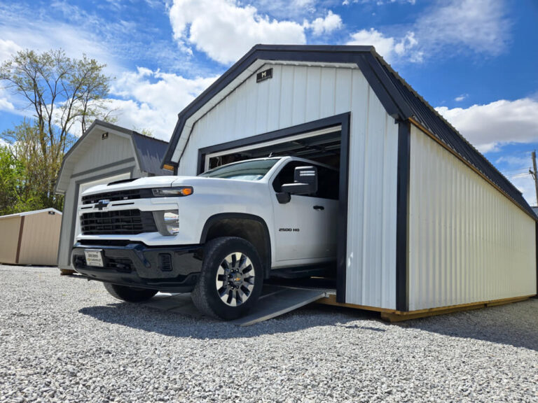 Lofted Garage white siding with dark trim and metal roof open garage door with truck pulling out
