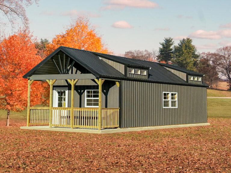 Swiss Cabin gray siding with black trim and metal roof sitting beside trees Featured