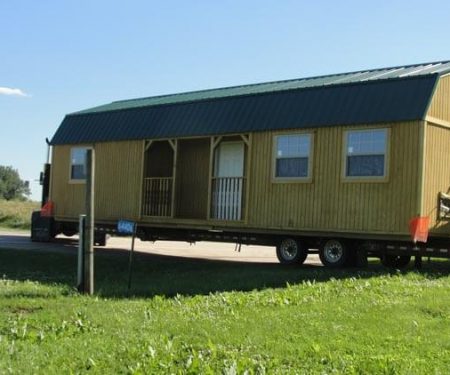 Stained Lofted Cottage with metal roof on a delivery trailer
