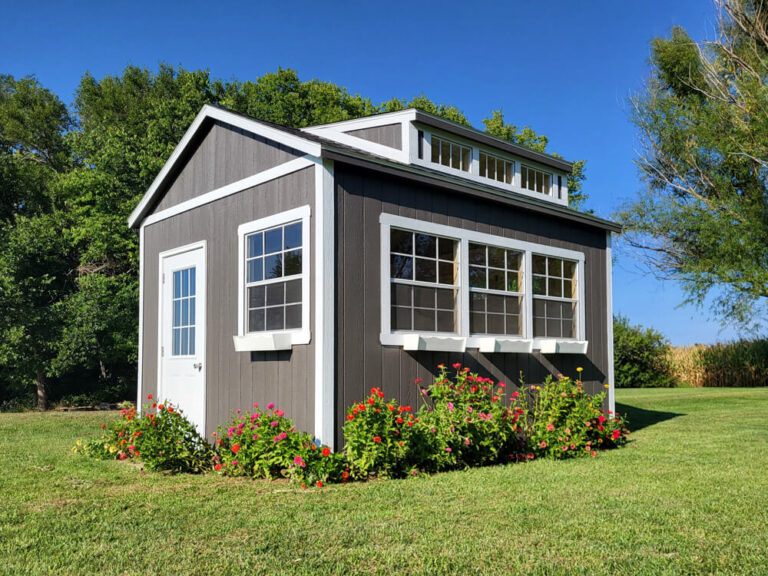 Villa gray siding white trim transom window in roof flowers around