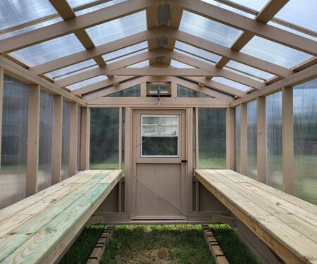 The inside of a greenhouse, with a door on the front wall, made by MidAmerica Structures